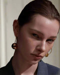 Stylish, young woman models Gold Statement Orb Hoop Earrings, angle 3