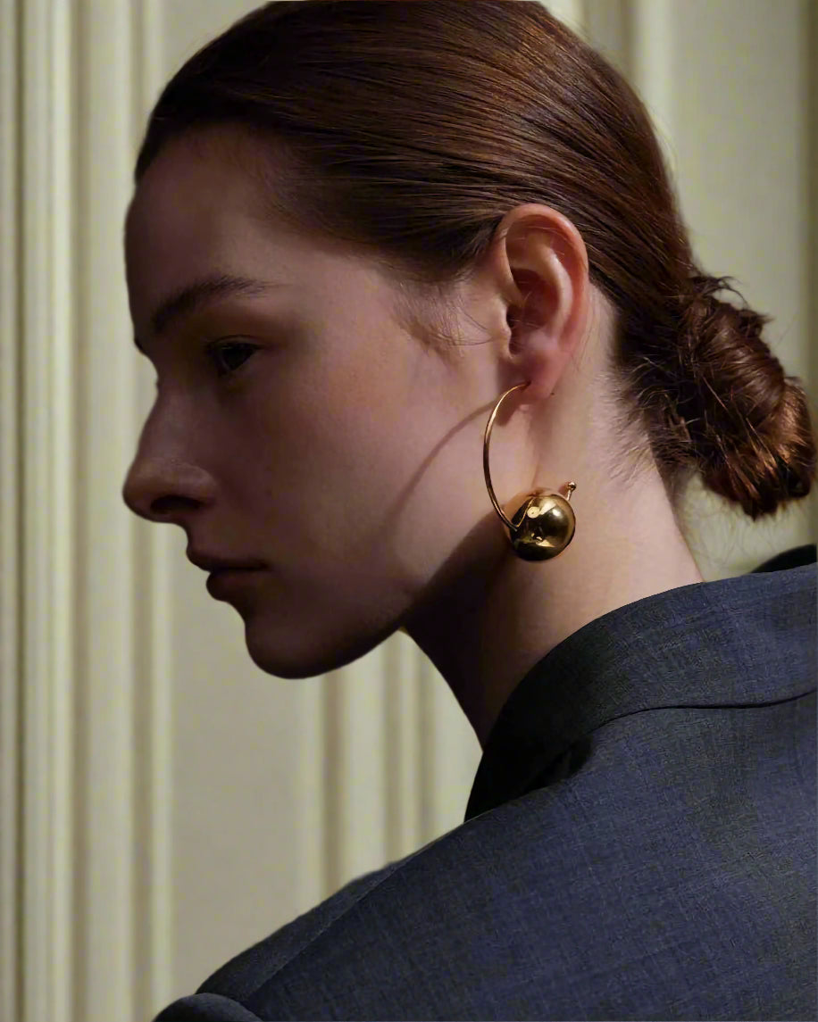 Stylish, young woman models Gold Statement Orb Hoop Earrings, angle 4