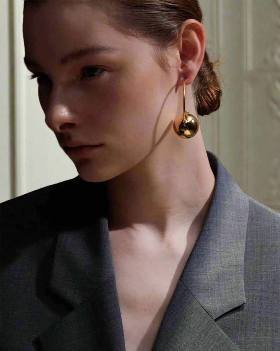 Stylish, young woman models Gold Statement Orb Hoop Earrings, angle 5