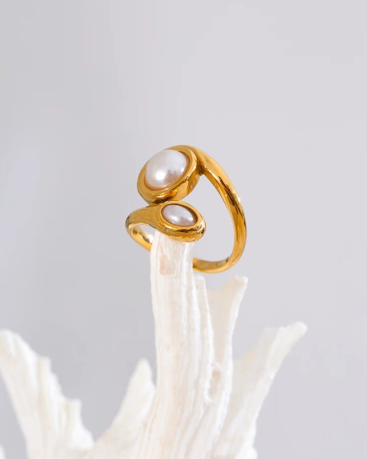 Gold Asymmetrical Bypass Pearl Ring, displayed over coral