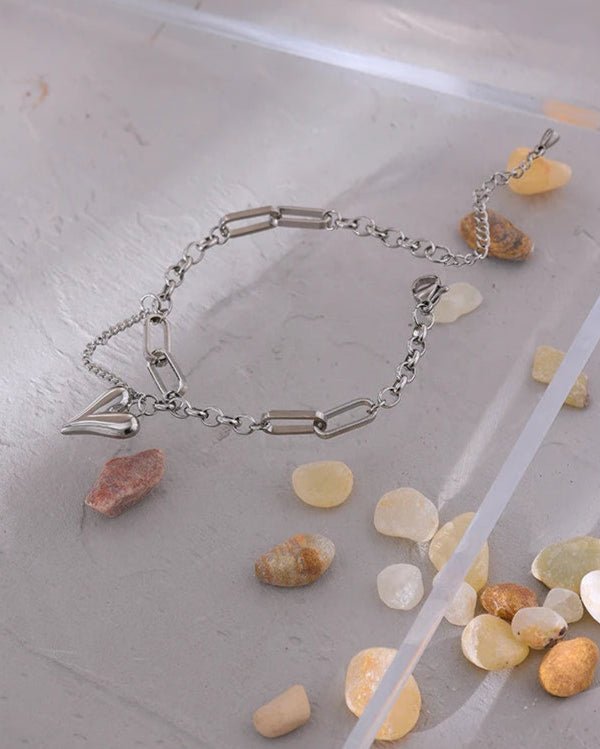 Silver Asymmetrical Heart Charm Bracelet on pink pebble display