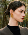 Elegant, young woman models Gold Butterfly Wing Statement Earrings, angle 2