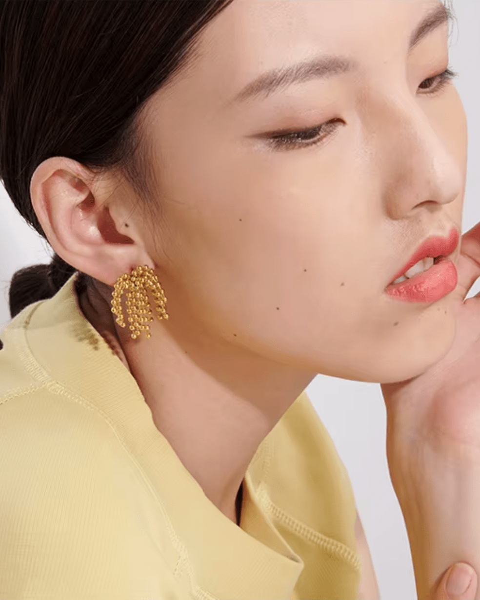 Young woman wearing Gold Cascading Ball Chain Drop Earrings, left