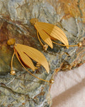 Floral Motif Dangle Earrings displayed on rock