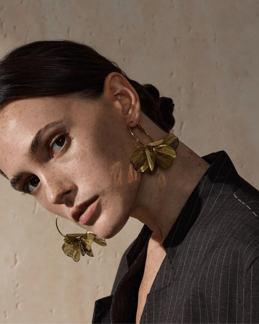 Elegant woman modeling Gold Flower Motif Hoop Earrings, profile