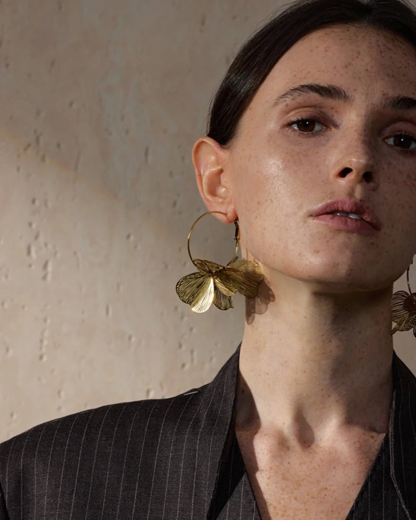 Elegant woman modeling Gold Flower Motif Hoop Earrings, close up